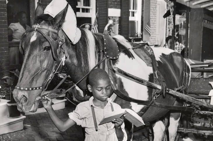 Pratt Library Book Wagon - historic photo of a boy reading a library book while holding the horse's bridle