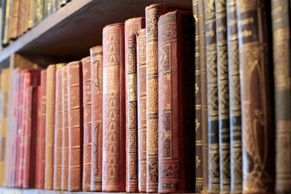 old books on a shelf with gold embossed leather spines