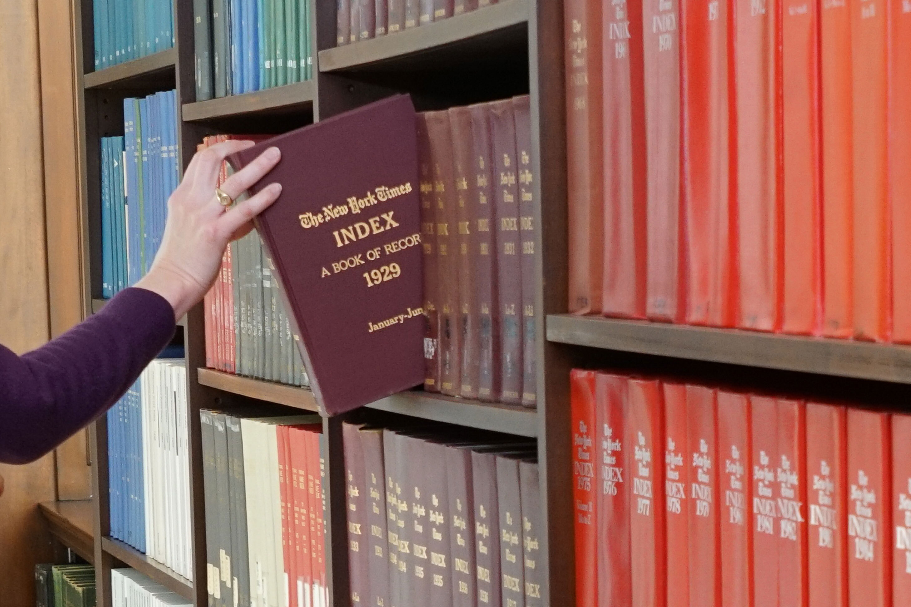 Periodicals - hand reaching for a bound volume of the New York Times Index, 1929