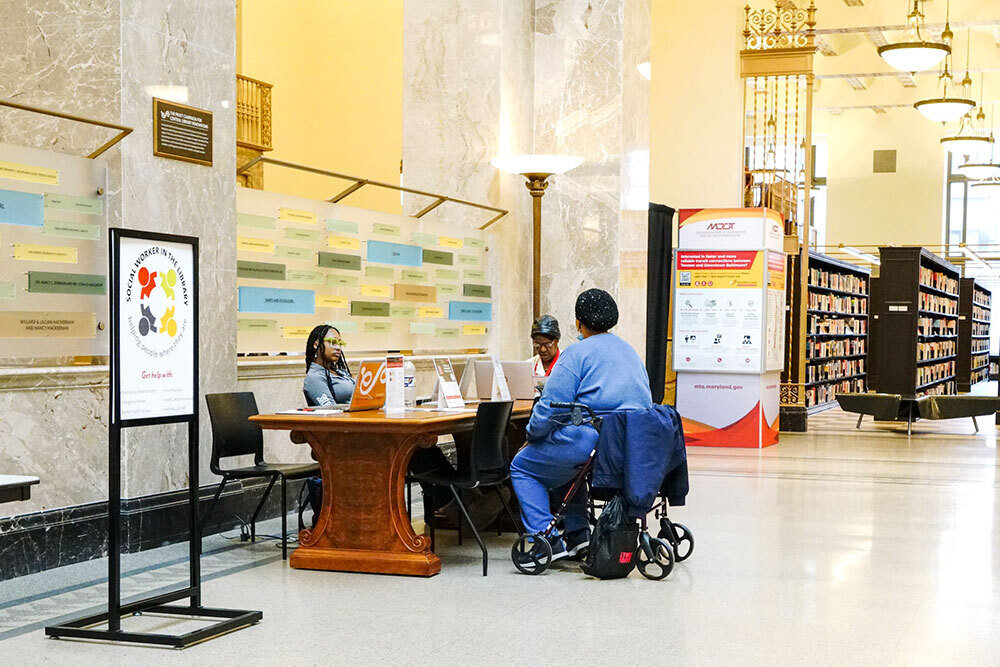 DEI programs  - social worker in a library consulting with a customer in a wheelchair