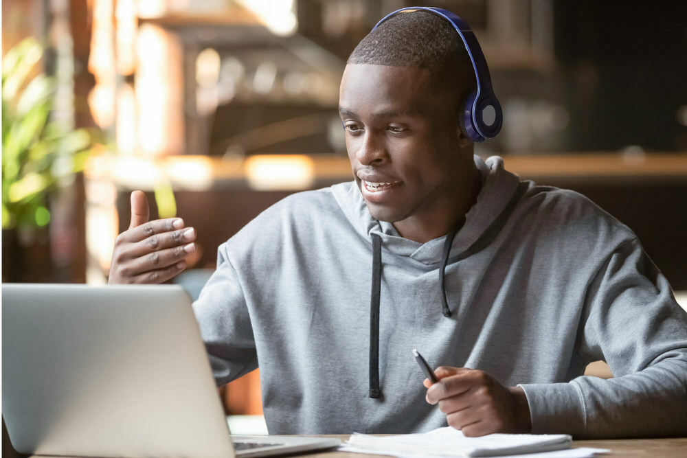 man speaking online with laptop and headphones