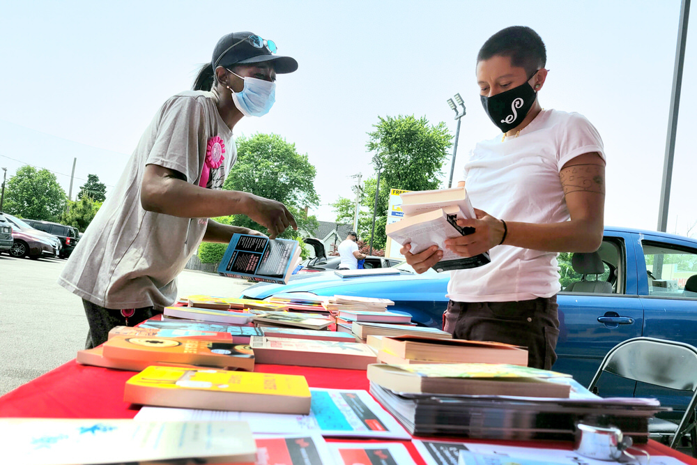 WaLi outdoor library service during COVID - two people wearing face masks with a table of books