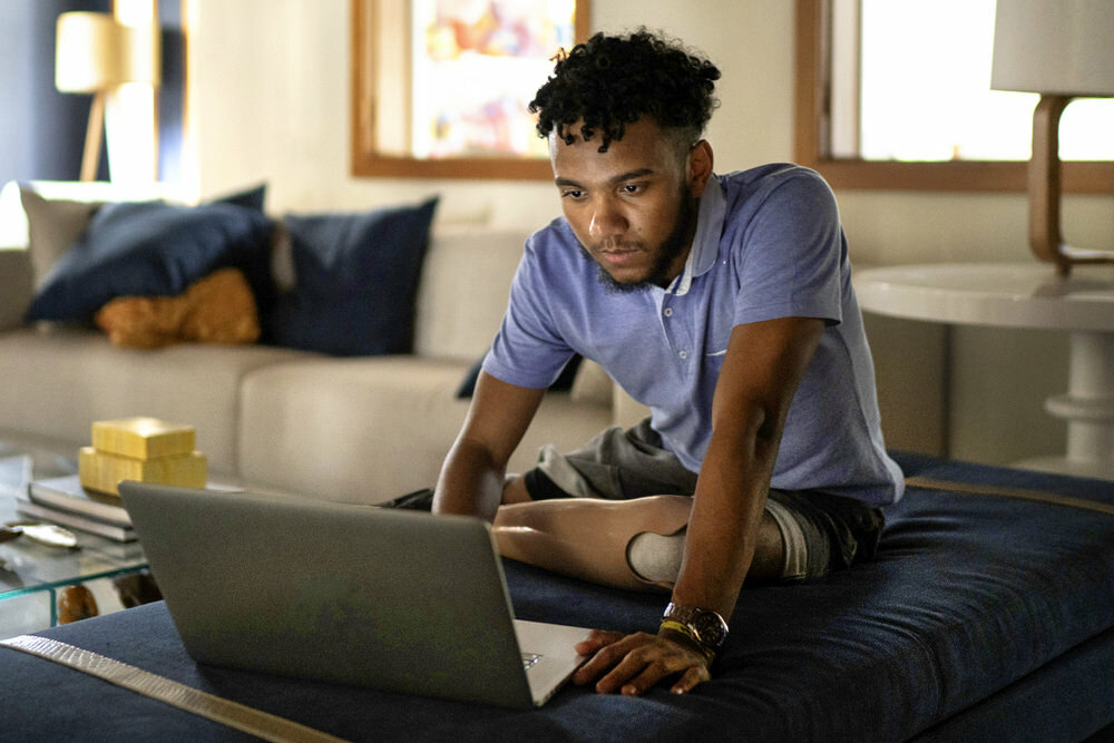 African American man at home man with laptop, he has a serious expression and prosthetic leg