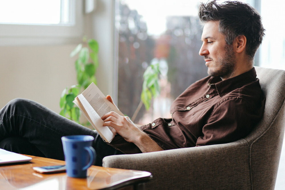 man reading at home with coffee and laptop