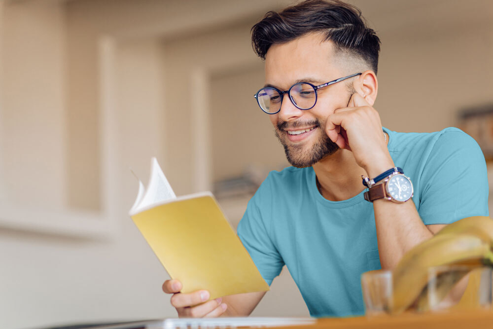 adult man reading a book with a slight smile