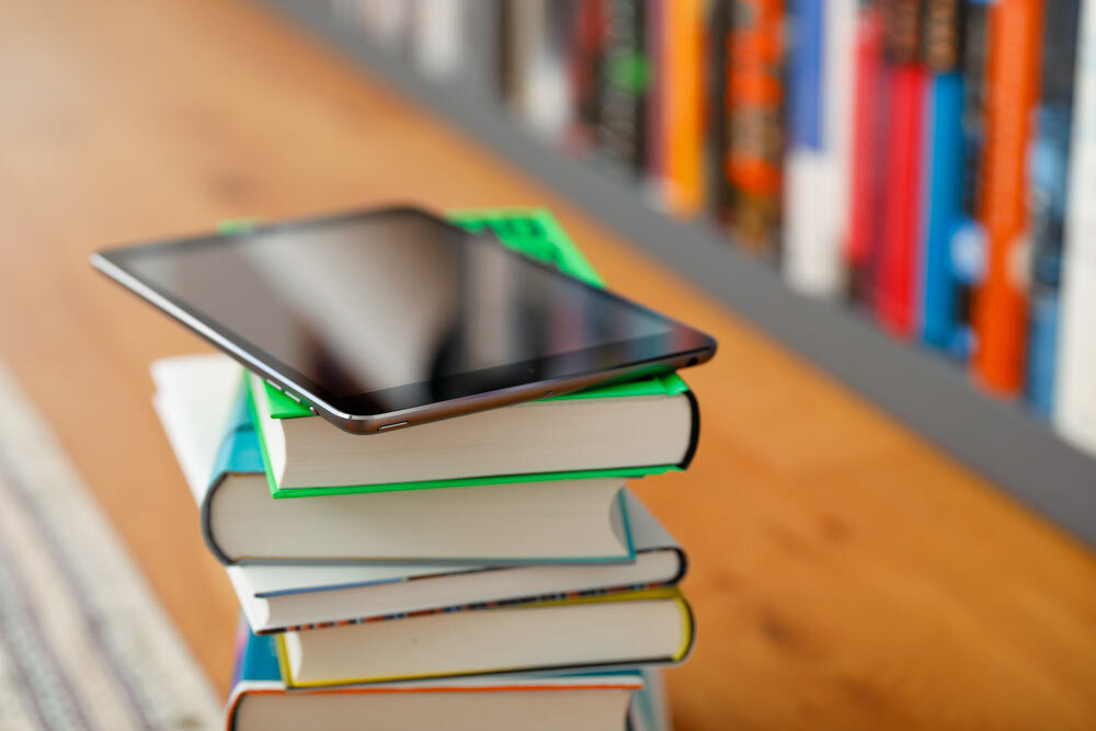 Books and more t the library - phone or digital tablet on a stack of books