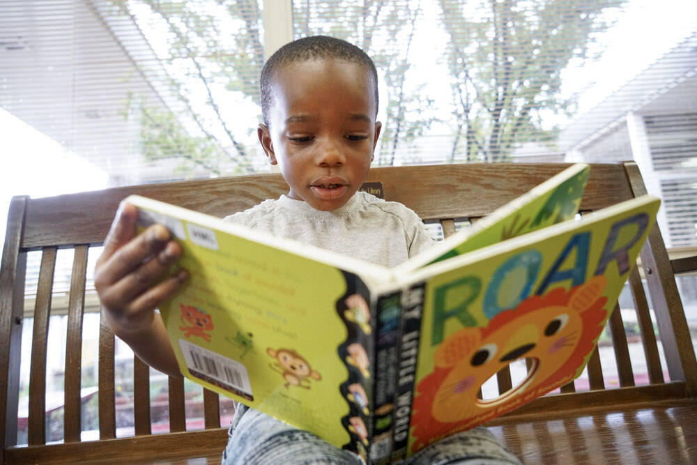 young child reading a library book
