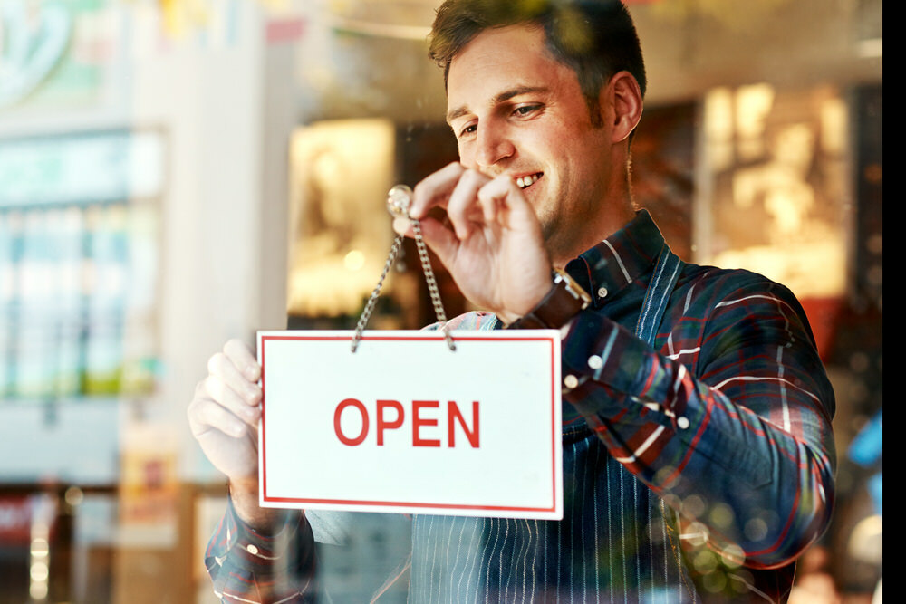 man haging OPEN sign at his business