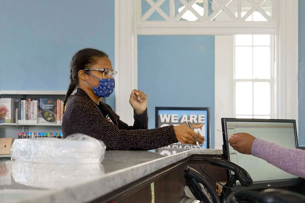 checkout at Hampden branch, with a customer wearing a mask and a library card being handed over