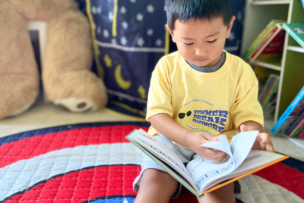 a child reading their free Summer Break book and wearing their T-shirt