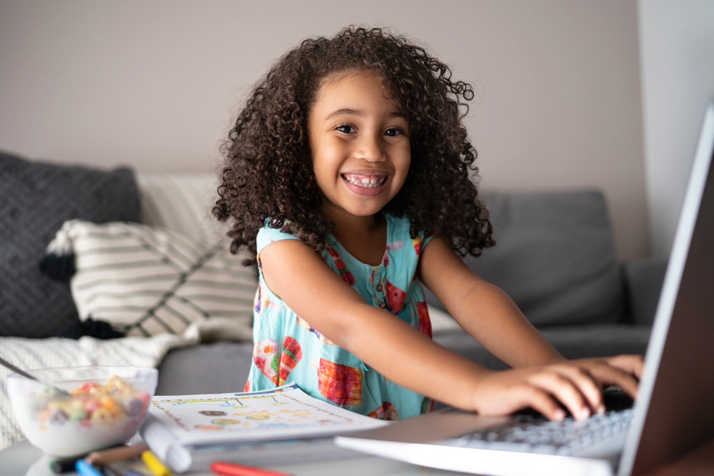 homeschool girl using a laptop computer, smiling