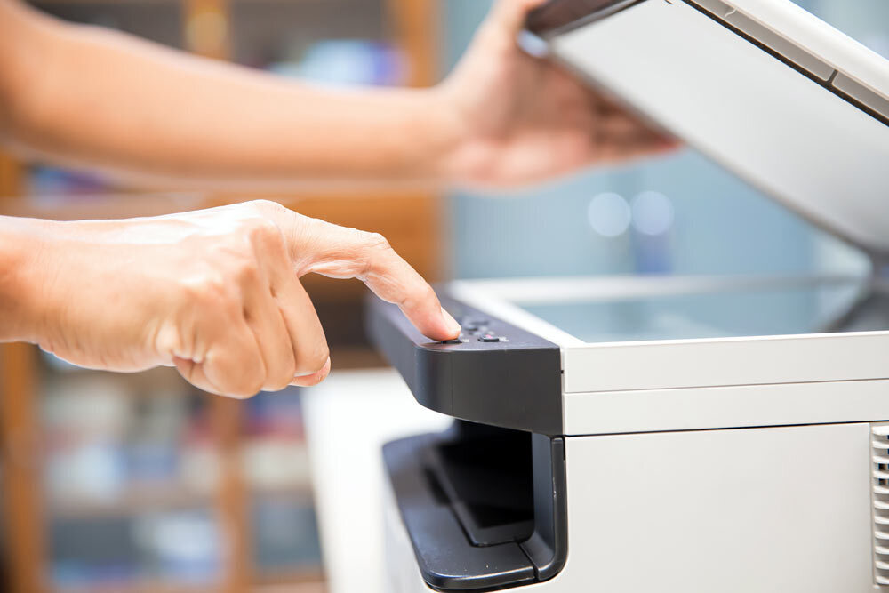 copier and printer closeup with hand on a button