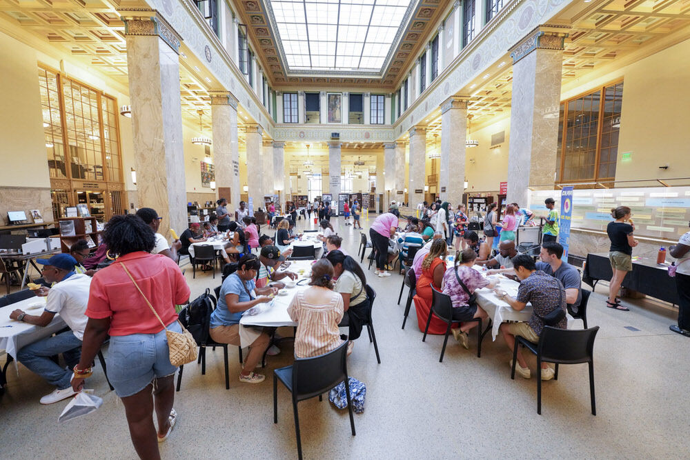people at tables in the Central Library at a creative community event
