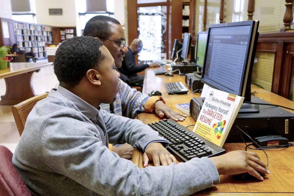 job searchers - adults using computers at Pratt Library with the Targeted Resume book