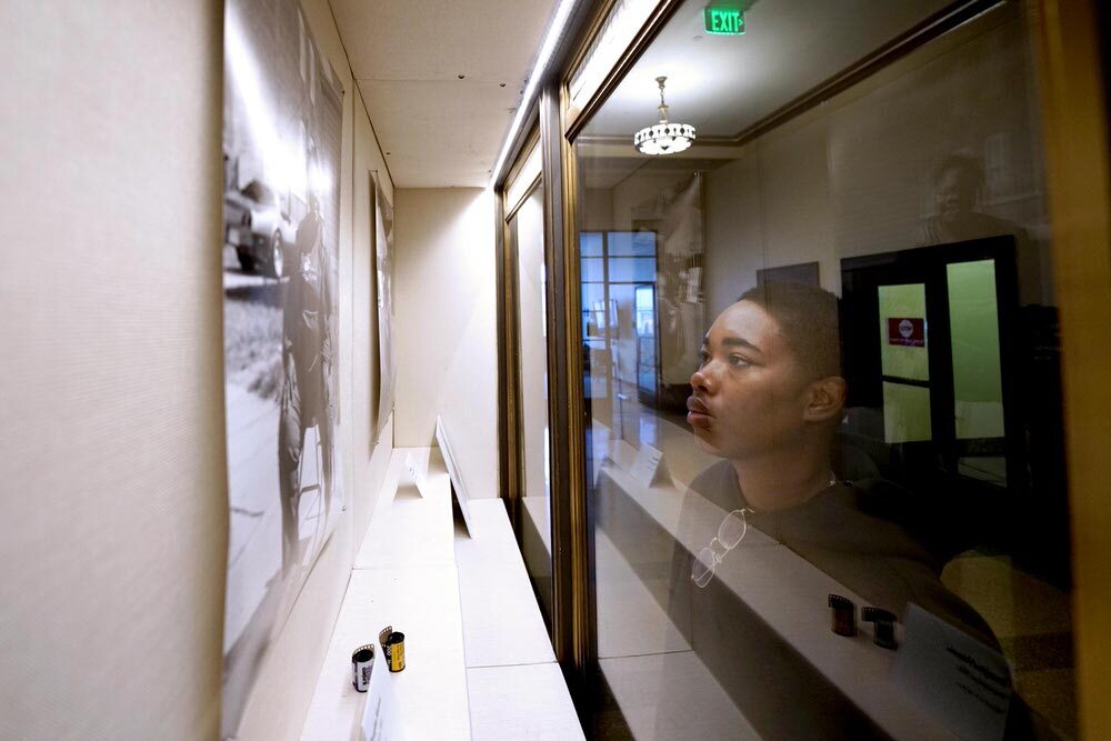 Artist in Residence SHAN looking at her exhibit window, with photographic film rolls on display