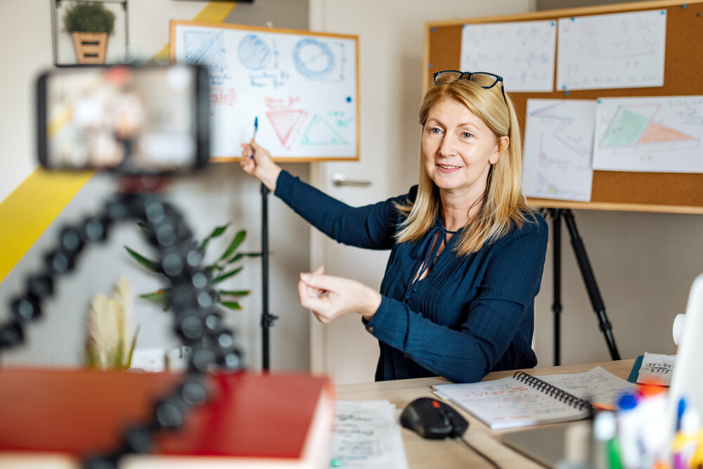 teacher preparing virtual online class with a whiteboard and video camera