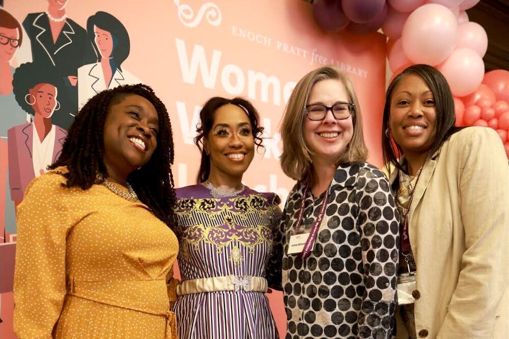 Women in Workforce Luncheon, 4 women posing by signs and balloons