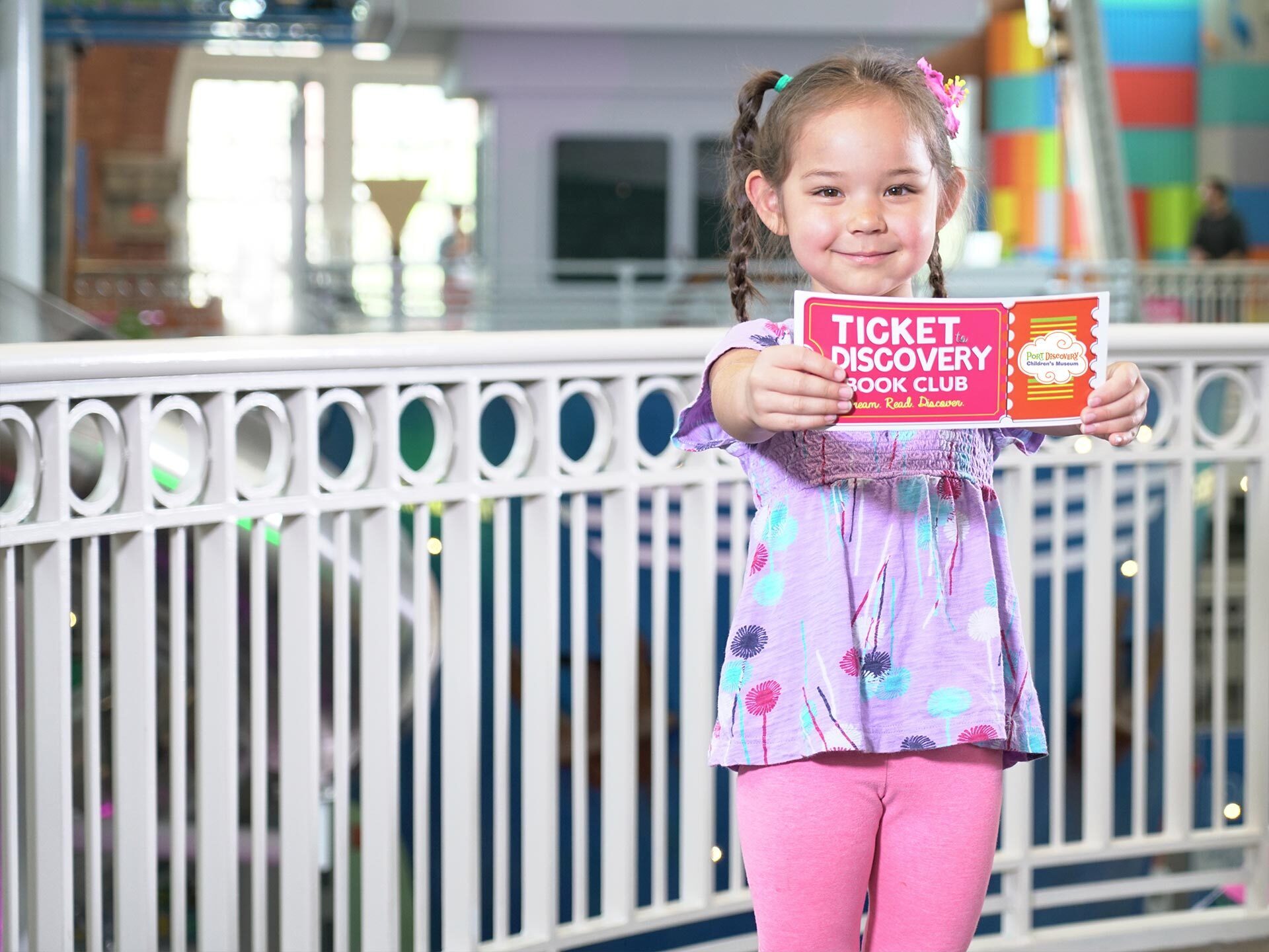 Tickets to Discovery - a young girl holding a colorful ticket the the children's museum