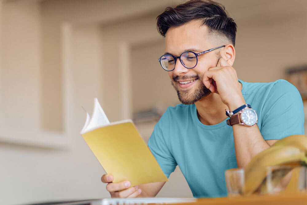 adult man reading a book with a slight smile