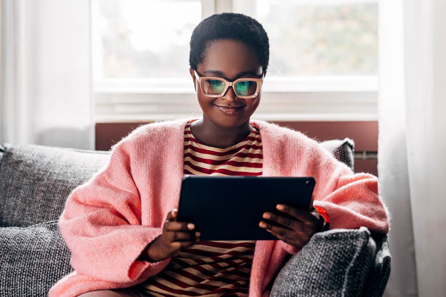 digital library - woman wearing glasses with a digital tablet smiling by a window