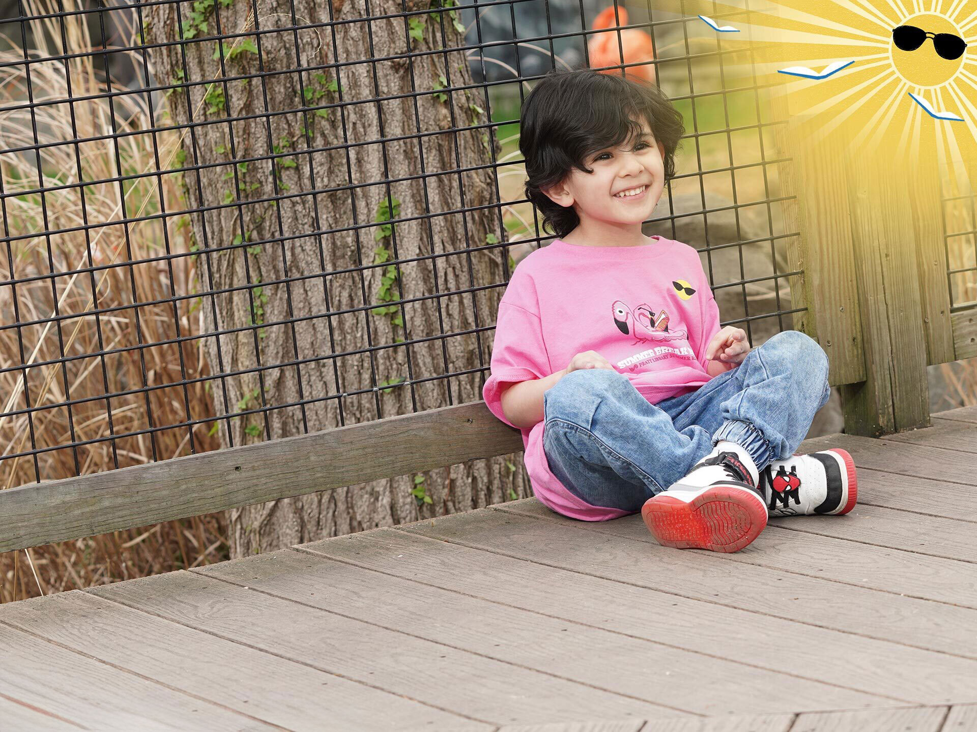 Summer Break Baltimore child wearing a 2025 t-shirt at the zoo with sun and flying books logo