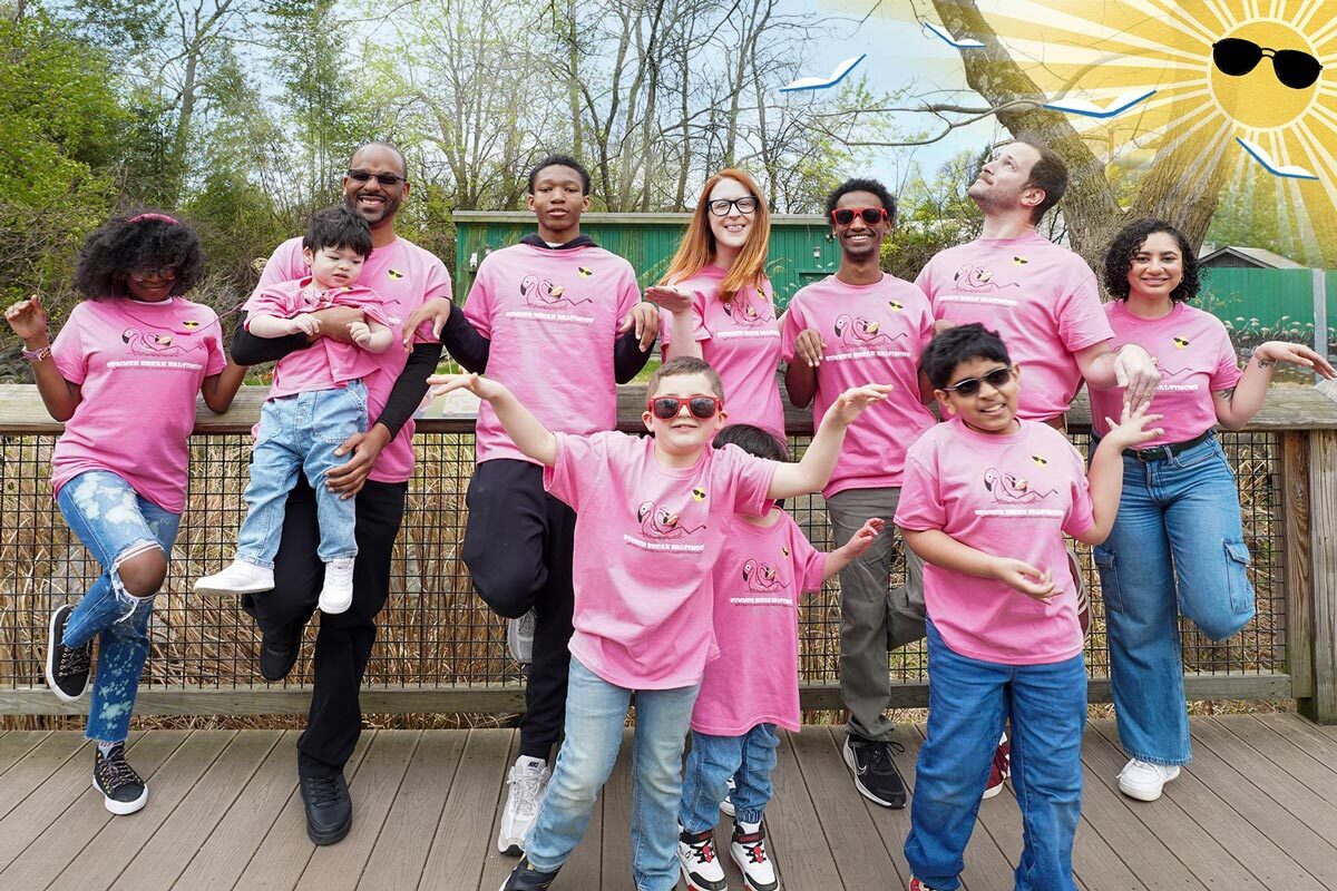Summer Break Baltimore group of people in their 2025 t-shirts at the zoo with sun and flying books logo