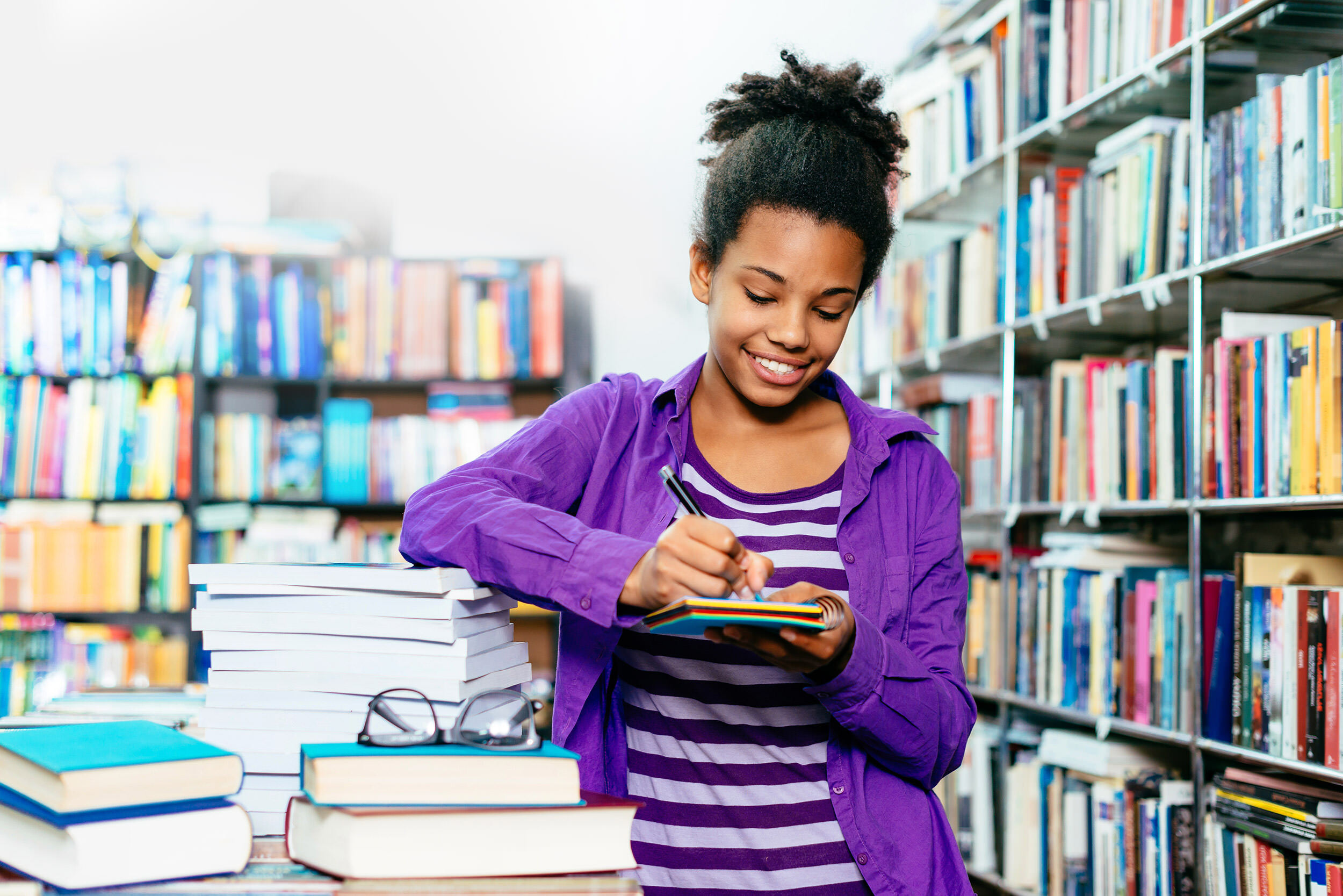 teens - a teenage girl surrounded by books, writing in a notepad