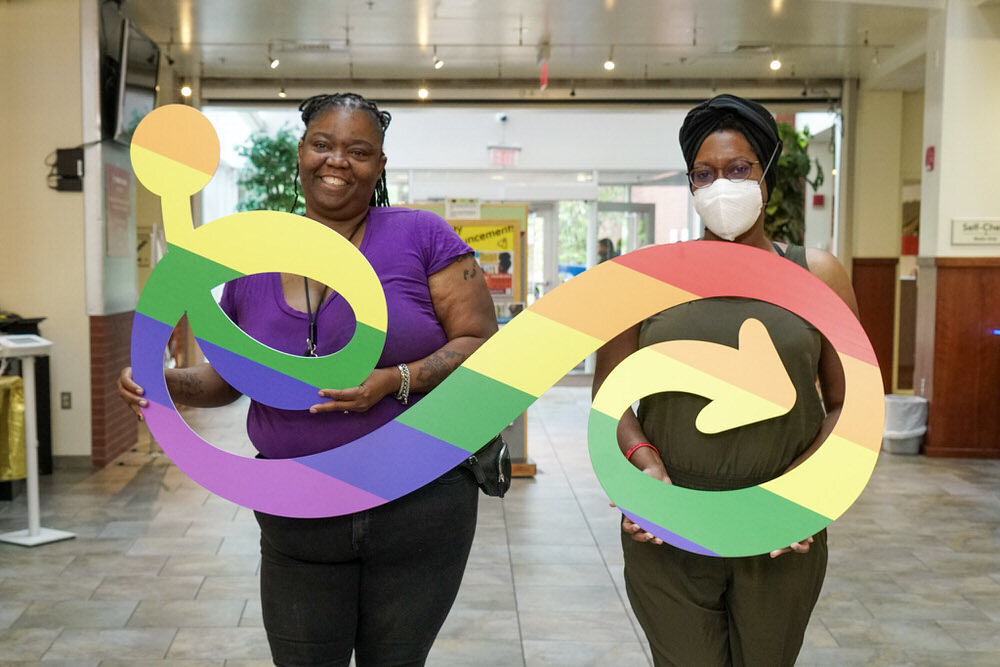 Pratt Pride - staff members holding a rainbow LGBTQ+ version of the Pratt logo