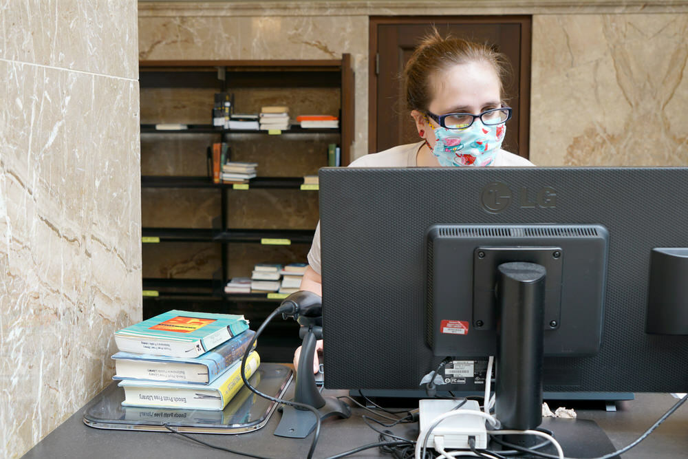library staff checking out books with a mask on during COVID-19