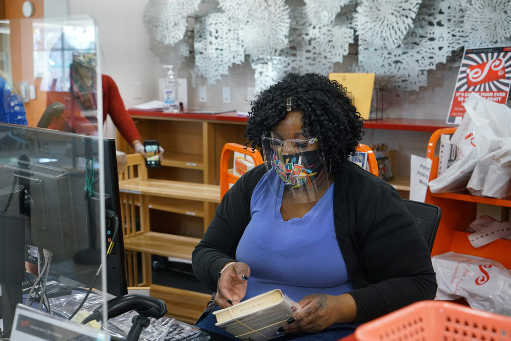 staff checking out books during the pandemic with a face mask and shield