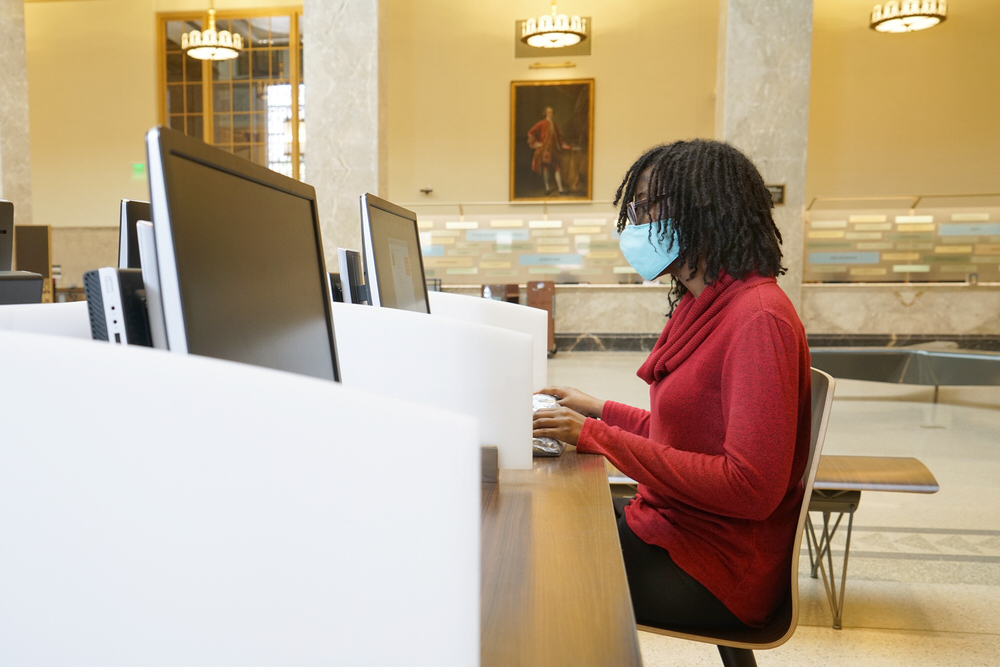 customer using public library computers with a face covering for safety