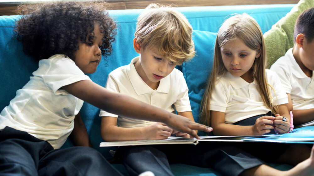 group of children on a couch sharing a book