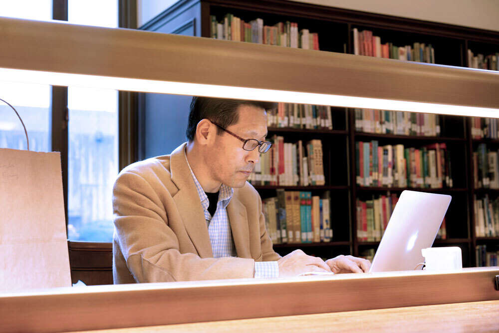 man doing research on a laptop at a table in Central Library