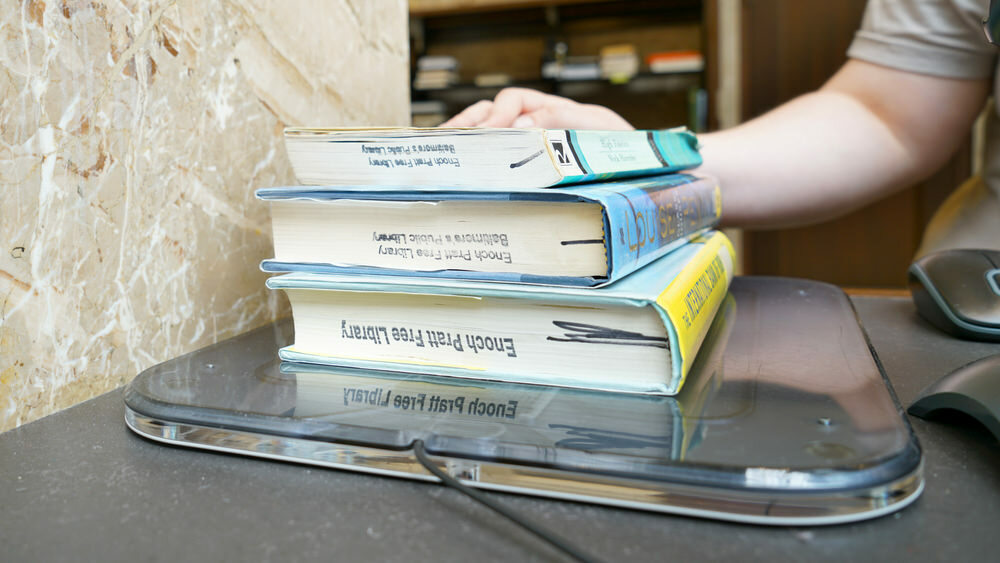 checkout desk at the library, books being scanned