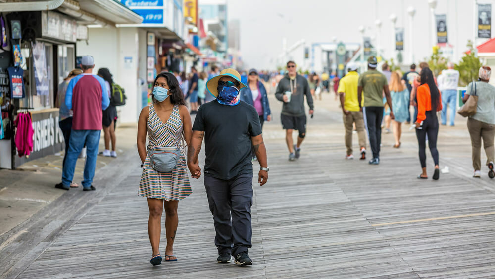 people with masks walking by Maryland businesses in Ocean City