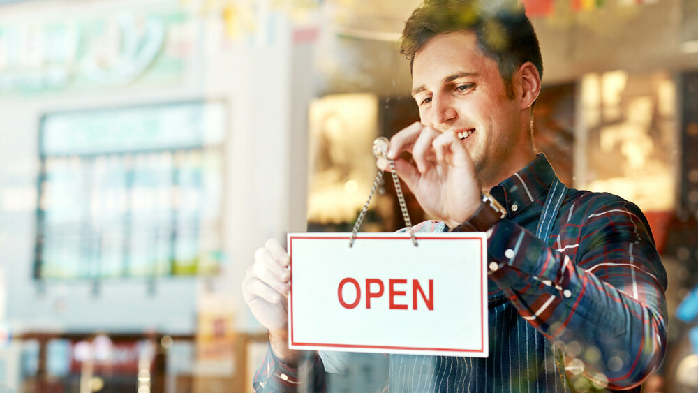 small business owner hanging an OPEN sign