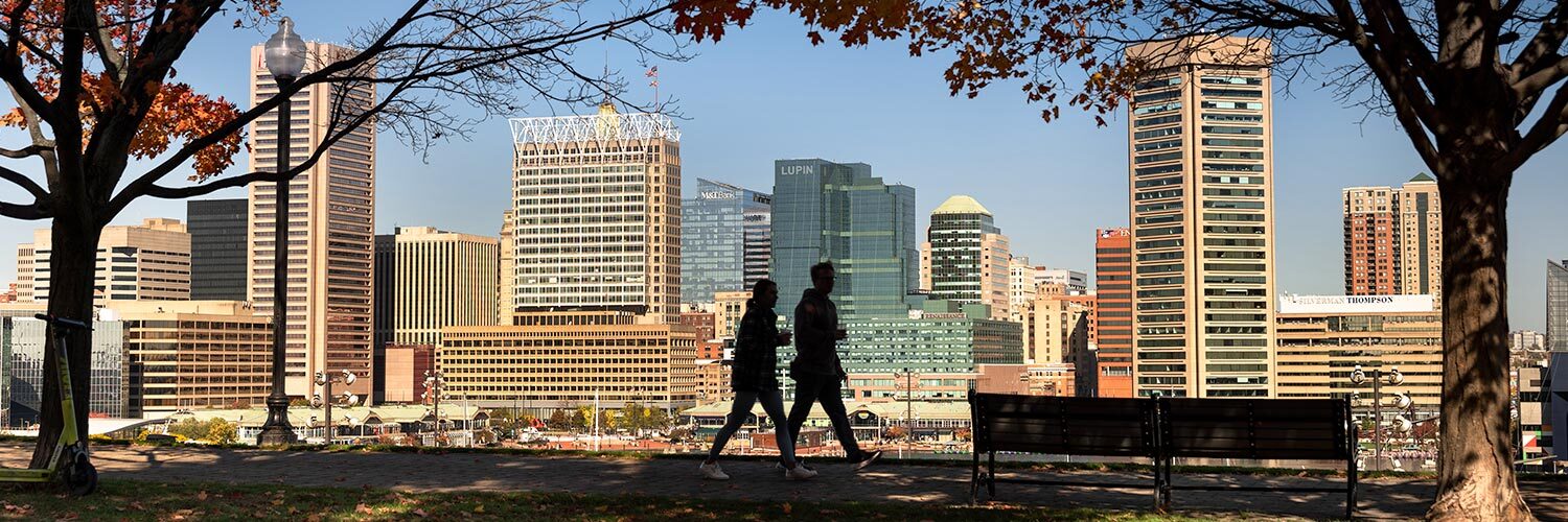 Baltimore City - silhouettes of people walking near buildings and green space