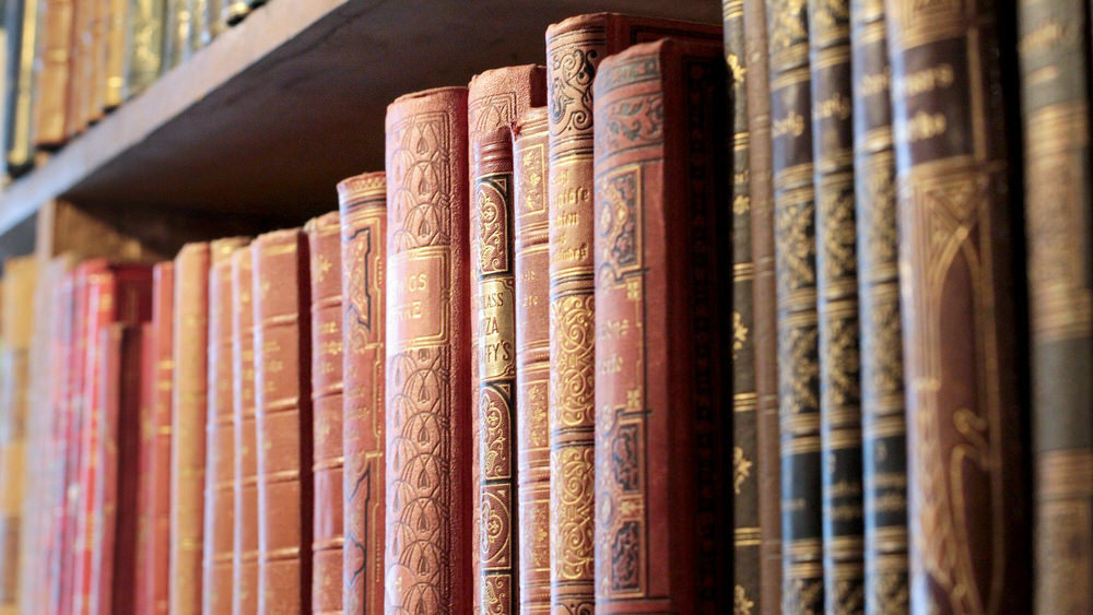 old books on a shelf with gold embossed leather spines