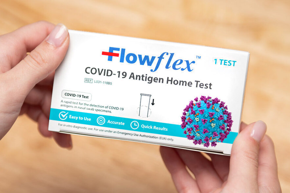 hands holding a box of a FlowFlex at-home COVID-19 test kit