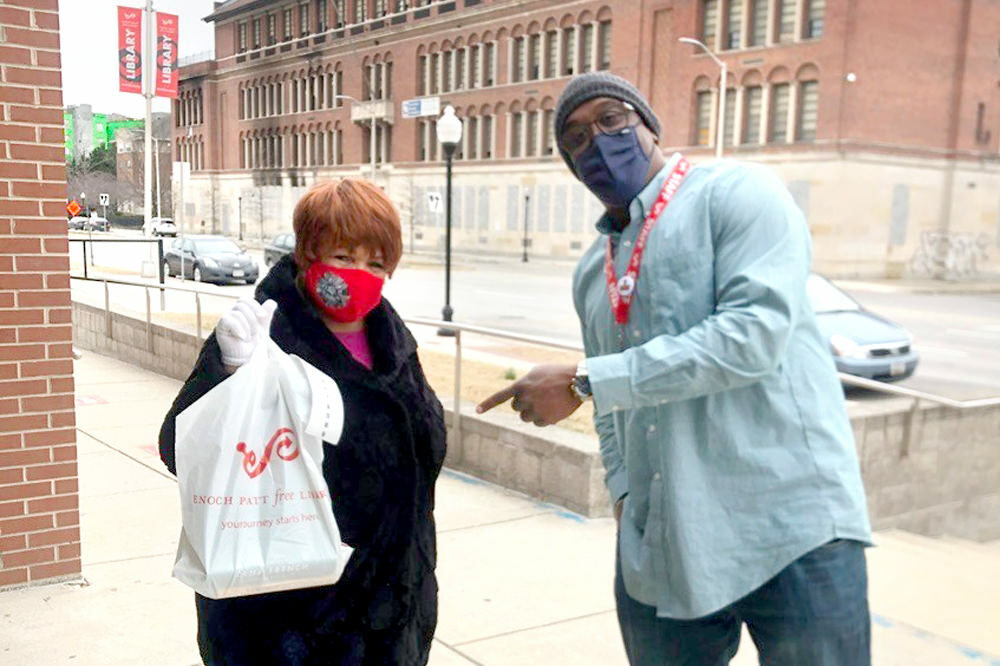 happy customer picking up Pratt Library materials in a bag, with staff outside