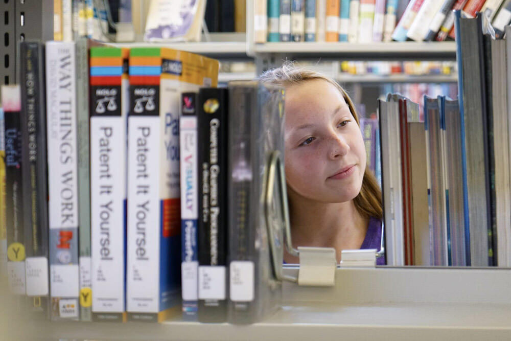 teen girl browsing library books.