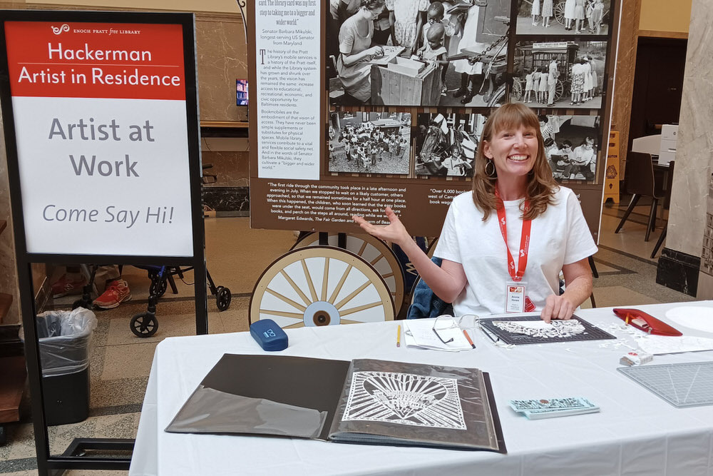 Annie Howe, artist working at the Central Library with Come Say Hi sign