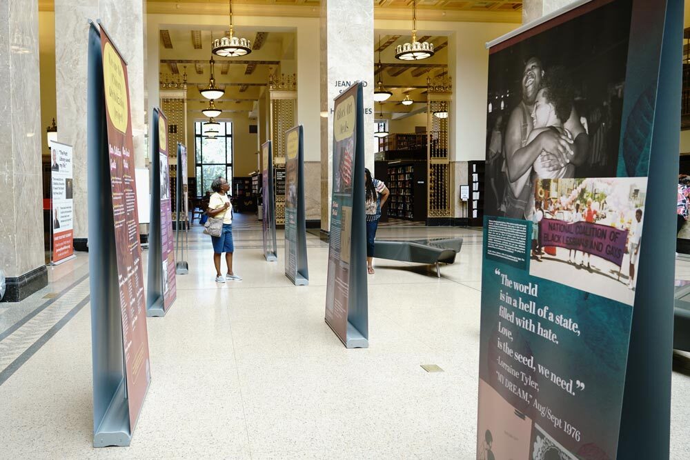 Soul of the Butterfly Chicory exhibit panels with a woman browsing between panels, wide view