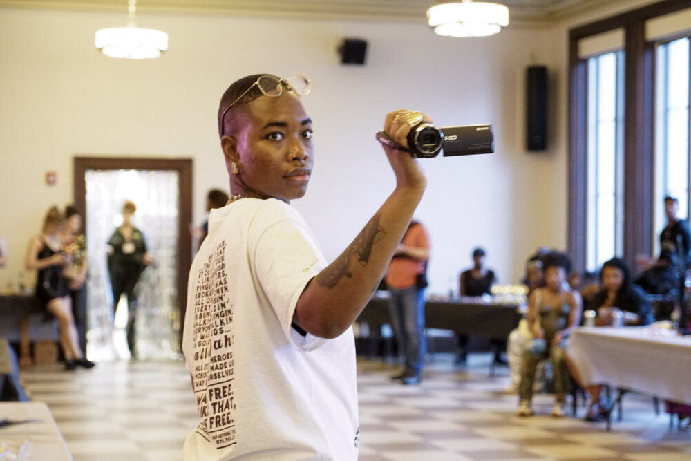 SHAN Wallace Artist in Residence at Pratt Library with video camera at an event
