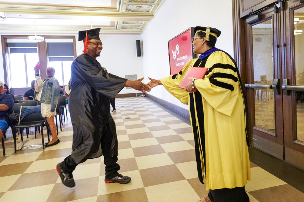 a graduate receiving his diploma from Career Online High School at Pratt Library