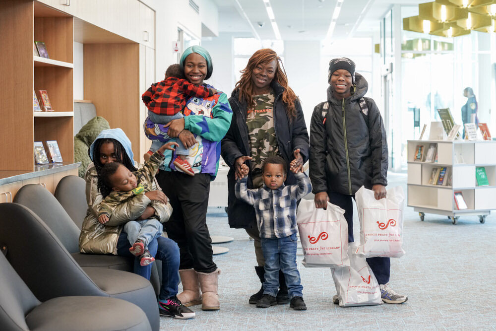 happy family at a Pratt Library branch with Pratt logo branded bags