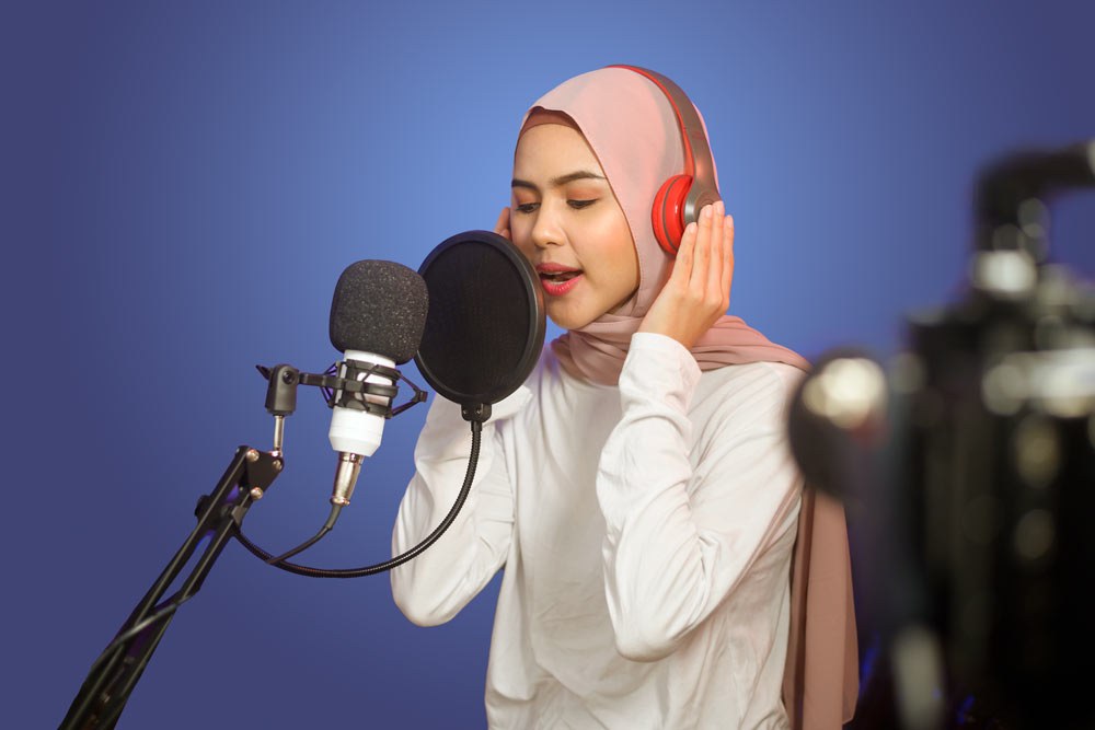 teen recording in a studio with headphones, a microphone and other equipment
