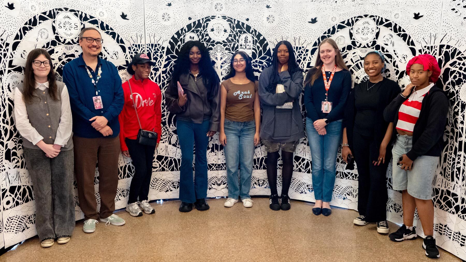 Teen board group with staff at Central Library by papercut wall art.