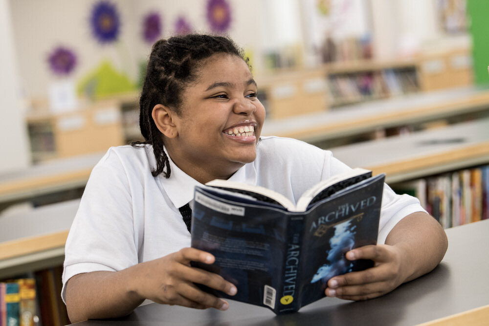 teen girl with a big smile and a library book.