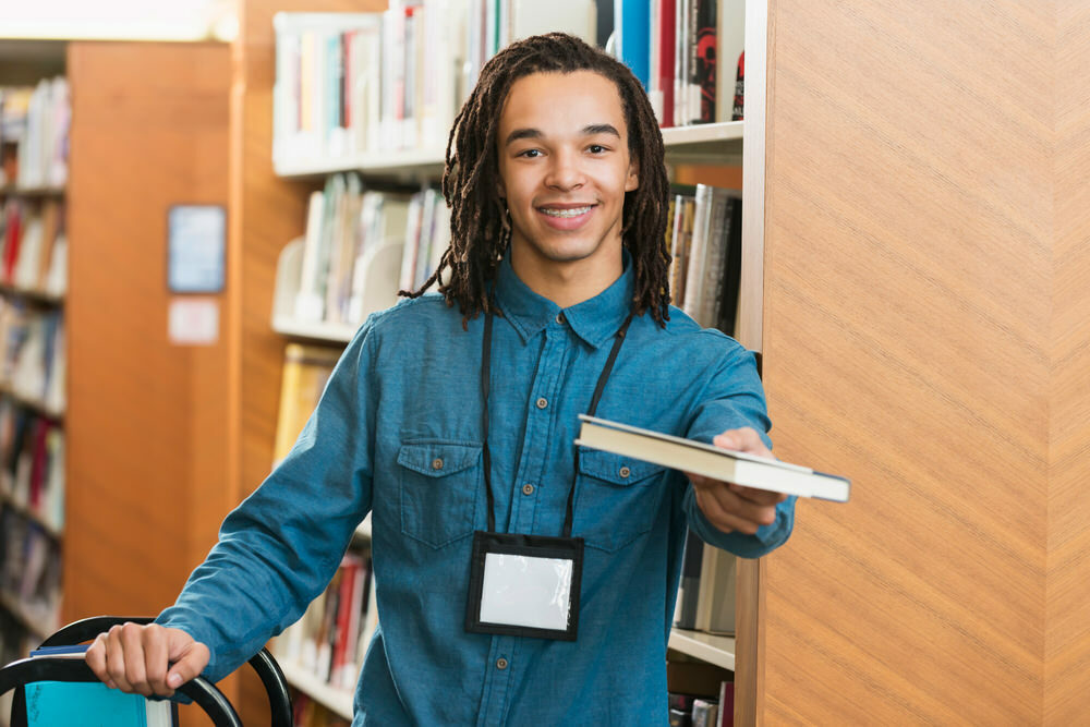 teen working in library with a book